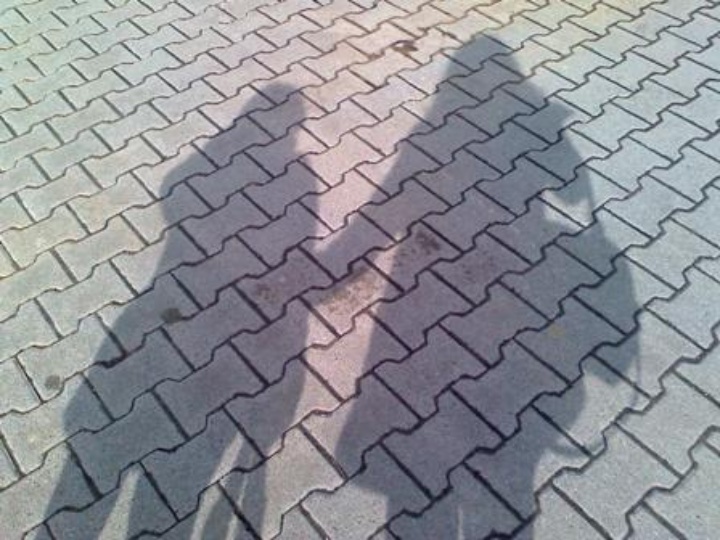 Das Bild zeigt die Schatten zweier Frauen auf der Straße, die nebeneinander stehen.