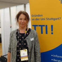 Edith Schmitt steht vor einem Plakat der Technologie-Transfer-Initiative