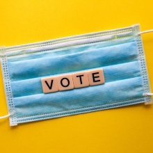 Auf dem Bild ist eine medizinische Maske mit dem Schriftzug "vote" zu sehen.