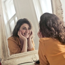 Junge Frau blickt glücklich in den Spiegel