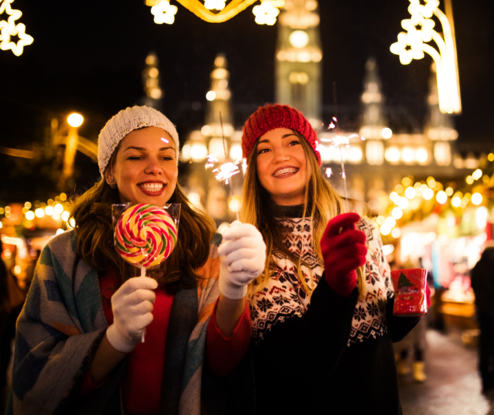 Two women having candies on a Christmas market. 